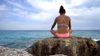 Sahilde Deniz arka plan üzerinde oturan kız arkadan görünüş