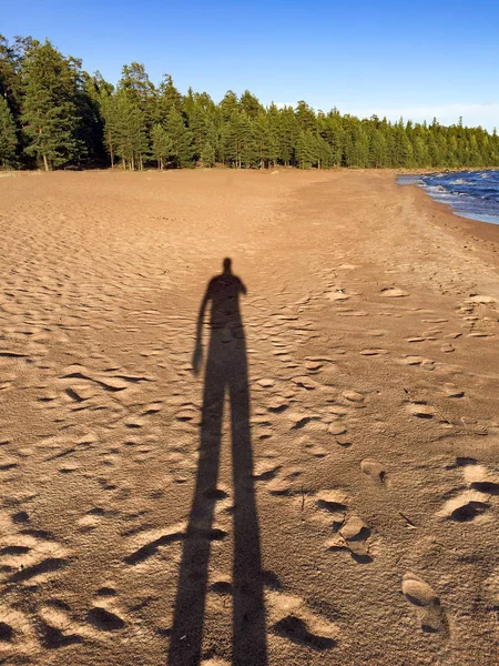 Man shadow on beach of Valaam island, Karelia, Russia