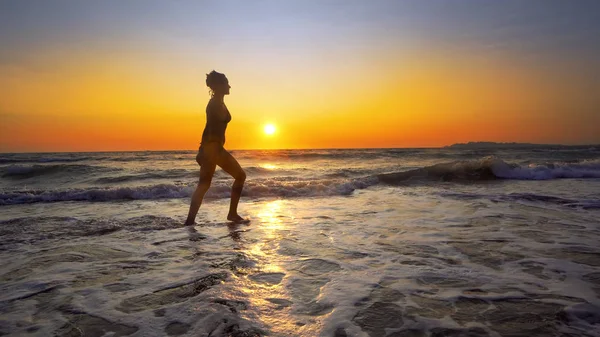 夕日を背景に海岸線に休暇を楽しむ女性 — ストック写真