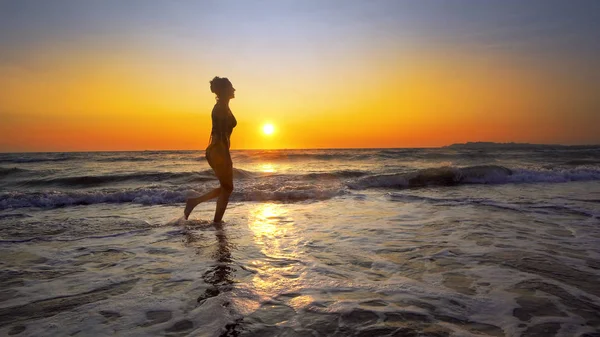 夕日を背景に海岸線に休暇を楽しむ女性 — ストック写真