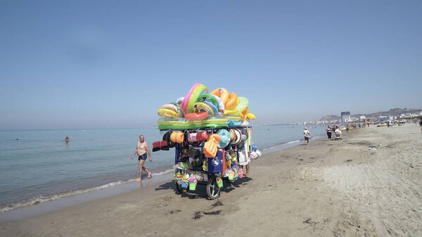 Дуррес, Албания - около августа 2017 года: Продавец купальников и игрушек для детей на пляже
