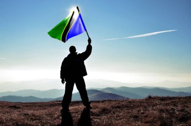 dağ tepe üstünde dalgalanan Tanzanya bayrak tutan adam silüeti