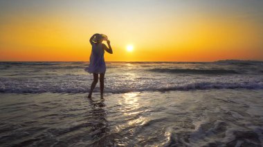 şapkalı günbatımı arka plan üzerinde beyaz elbiseli kadın