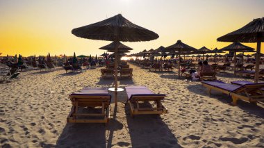 Boş plajda şezlong ve ahşap harika gün batımı tutuyor