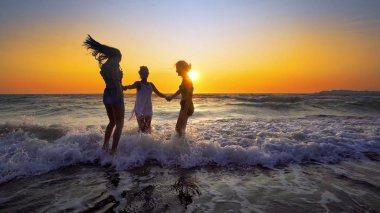 Mutlu kız eğlence günbatımı arka plan üzerinde sahilde dalgalar deniz sahip Grup