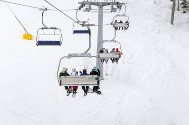 İnsanlarla yolculuk sandalye teleferik dağa birlikte yakından birbirine bir eğleniyor otururken zaman snowboard bir gün boyunca