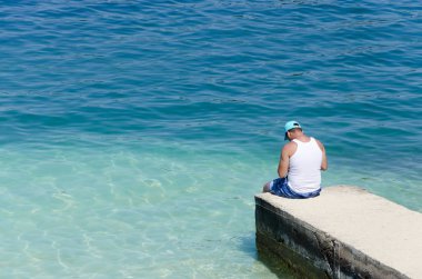 Rıhtımda kimliği belirsiz balıkçılar oturuyor.