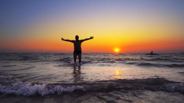 Tanımlanamayan siluet, okyanustan gün batımı suyunda elleri açık olarak yürür, FREEDOM CONCEPT, steadicam cinematic shot