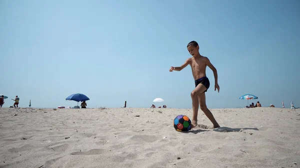 男孩白天在沙滩上踢足球 — 图库照片