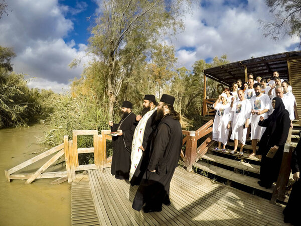 YERICHO, ISRAEL - 20 FEB, 2017: Religious christians with white clothes going into the water of the Jordan river at baptismal site Qasr el Yahud near Yericho