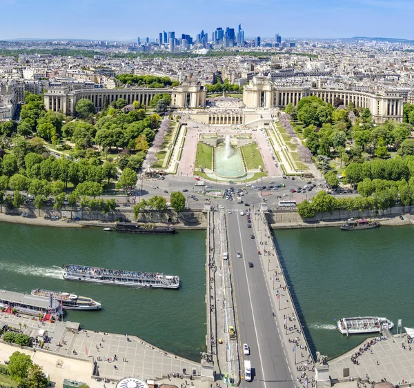 Aerial panoramic view of Paris traffic with boats on Seine river and vehicles on D\'lena bridge, Trocadero with Chaillot Palace fountains and gardens and La defense contemporary business center skyscrapers at background horizon