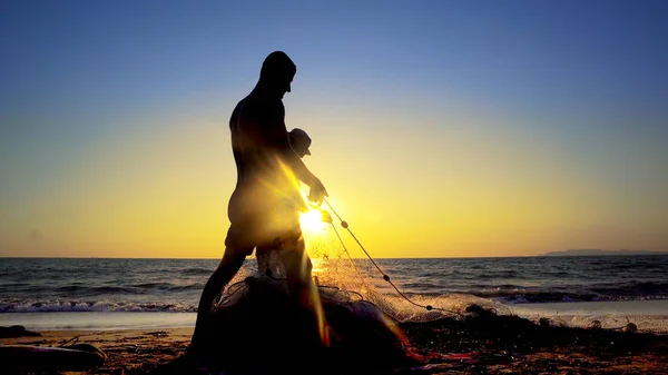 夕日を背景にネットを釣りと漁師のシルエット — ストック写真