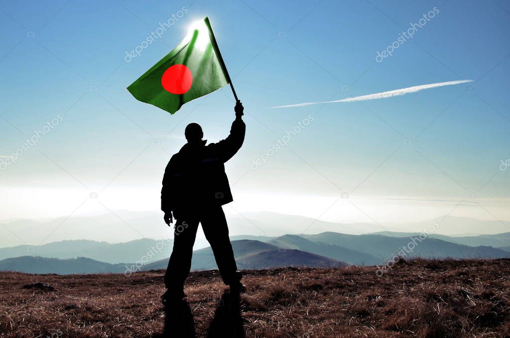 silhouette of man holding waving Bangladesh flag on top of mountain peak
