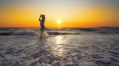 şapkalı günbatımı arka plan üzerinde beyaz elbiseli kadın