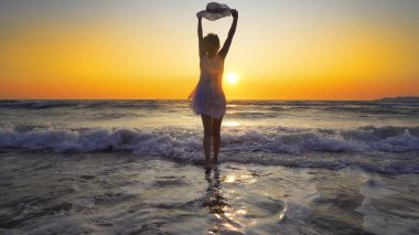 şapkalı günbatımı arka plan üzerinde beyaz elbiseli kadın