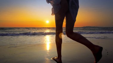 Kumsalda gün batımı arka plan üzerinde yürüme beyaz elbiseli kadın