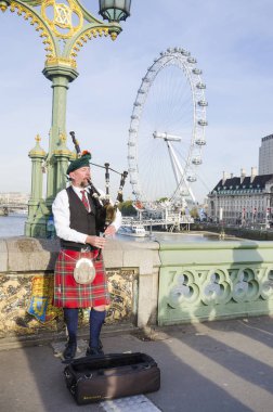 LONDON, UK - NOE, 2016: Londra 'daki Westminster Köprüsü' nde kimliği belirsiz bir gaydacı. İngiltere 'de Great Highland gayda genellikle orduda kullanılır ve genellikle resmi olarak çalınır. 