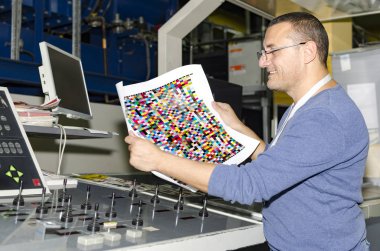 Operator checking color proofs for printing, during production clipart