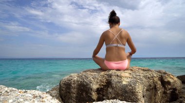 Sahilde Deniz arka plan üzerinde oturan kız arkadan görünüş