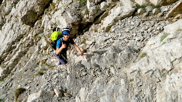 Young man wearing in climbing equipment climbing on a stone rock outdoor