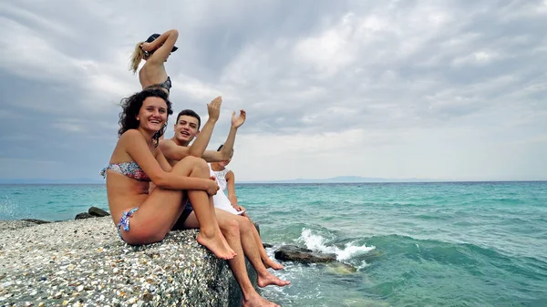 夏の休日日を有し楽しみに桟橋で海の近く座っている陽気な若い十代の若者たち — ストック写真