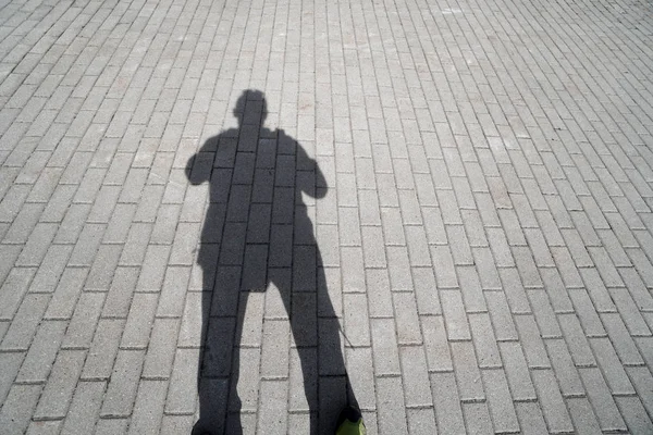 Man shadow on concrete pavement walkway, pov