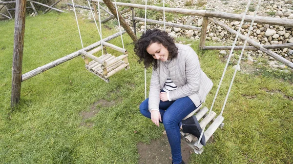 Belle Adolescente Aux Cheveux Bouclés Assoit Sur Balançoire Sourit Discrètement — Photo