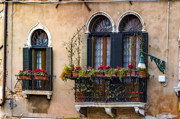 Old balconies in a Venice colorful building with red flowers