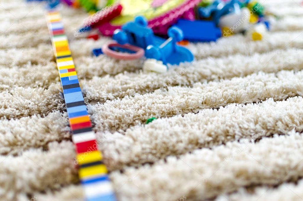 Children play concept. Toy colorful plastic blocks on carpet with dof background