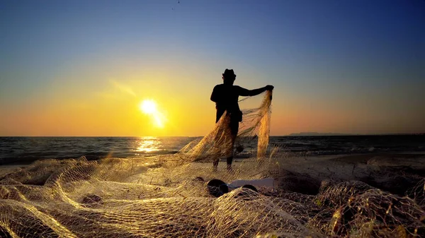 fisherman silhouette with fishing net on sunset background