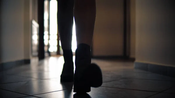 silhouette of female legs of in boots walking in corridor