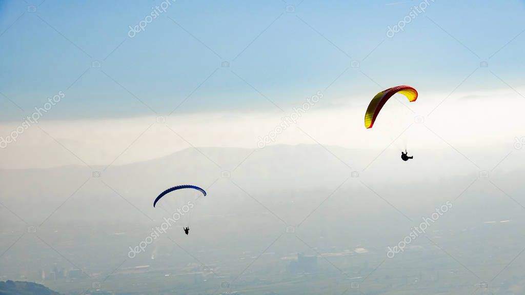 paragliders flying over valley in summer sunny day