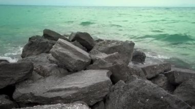 Bir sprey, ağır çekim şekillendirme taşlı bir kumsalda kırma dalgalar