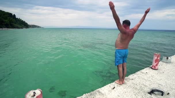 若い男性 代ヘッドは ターコイズ ブルーの海 スローモーションでジャンプします — ストック動画