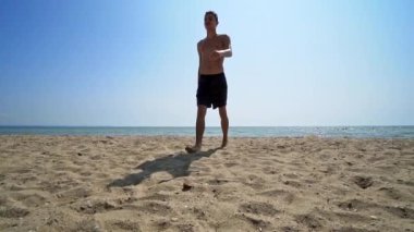 Handsome athlete male walk out of water on sea beach, cinematic steadicam shot, SLOW MOTION