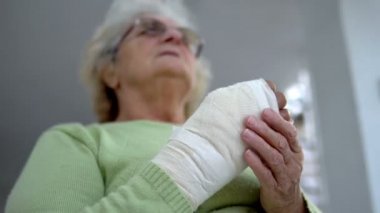 Yaşlı kadın yaralı eline masaj yapıyor. Oturuyor, sinemasal olarak.