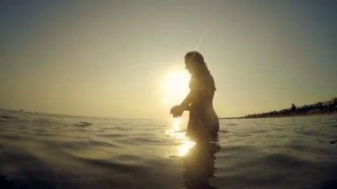 Atma siluet kız deniz günbatımı, ağır çekim, içine çakıl taşı taş, atlama