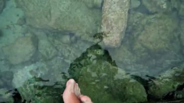 İskele ve salıncak feet su yüzeye yakın kenarında oturan deniz tarafından adam rahatlatır