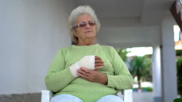 Droevige Oude Vrouw Heeft Pijn Zitten Houdt Haar Gewonde Hand — Stockvideo