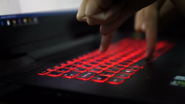 暗闇の中で赤いキーボードとラップトップ上の 本の指で入力します クリップを閉じます 人工的な光 夜遅くまで仕事 ハッカー クラッカーです エンジニア — ストック動画