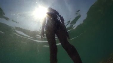 Seksi fitnes kızın onu bikini takım elbise arkadan aydınlatmalı güneş ışınları tarafından sıcak yaz günü Yüzme temizlik sualtı görüntüleme