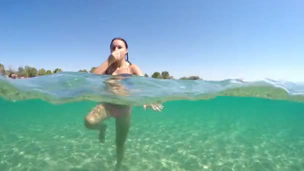 속에서 수영하는 재미있는 소녀가 웃으며 카메라 앞에서 키스를 모습은 행복하다 — 비디오