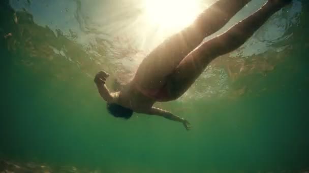 魅力的なフィット十代の海の水の表面で横になっています 夏の太陽の下から水中ビュー光輝く女の子スポーツマン体型 — ストック動画