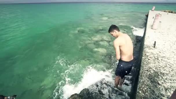 男性青少年湿自己与海水在码头楼梯上清爽 — 图库视频影像
