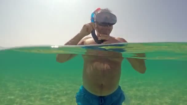 男子戴上浮潜面具 在海面上游泳 小光半水下景观 — 图库视频影像