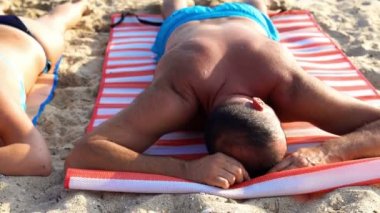 Bikinili yorgun mülteci ailesi kumsalda uyuyor.