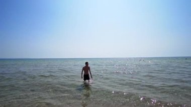 Handsome athlete male walk out of water on sea beach, cinematic steadicam shot, SLOW MOTION
