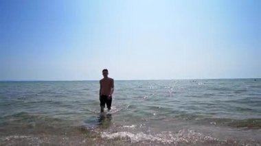 Yakışıklı sporcu erkek, deniz sahilinde sudan çıkıyor. Sinema filmi gibi.