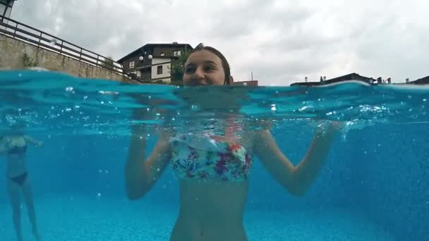 小女孩在游泳池里玩的很开心 笑着对着镜头张开嘴 半边天圆顶在水下 慢动作 — 图库视频影像
