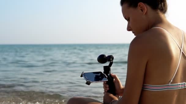 魅力的な女性の記録ビデオとともに現代的な3Dジンバル安定化カメラOsmoとスマートフォン — ストック動画